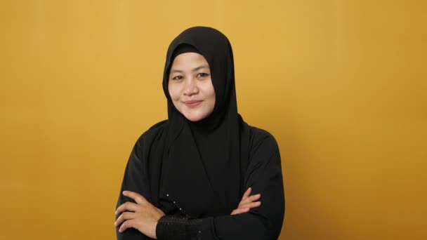 ヒジャーブを身に着けているアジアのイスラム教徒の女性の肖像は 黄色の背景を背景に 腕を越え 自信を持ってジェスチャー 成功したビジネス女性と優しい笑顔 — ストック動画