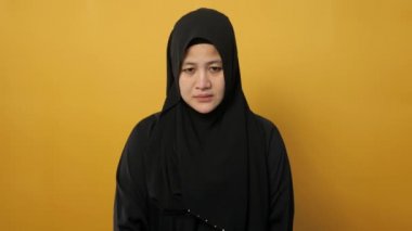 Asyalı üzgün Müslüman kadının portresi sarı arka planda ağlıyor, üzüntü bunalımı ümitsiz konsept