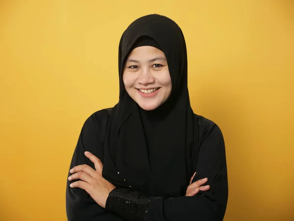 ヒジャーブを身に着けているアジアのイスラム教徒の女性の肖像は 黄色の背景を背景に 腕を越え 自信を持ってジェスチャー 成功したビジネス女性と優しい笑顔 — ストック写真