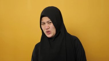 Asyalı güzel bir kadının portresi. Sarı arka planda elleri havada, teslim olmuş yüz ifadesinden korkan bir kadın.