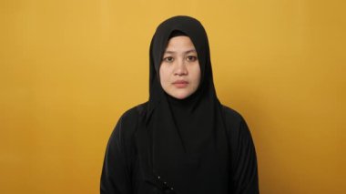 Genç Asyalı Müslüman kadın şok edici bir jest. Gördüklerine inanamıyor. Endişeli ifade, sarı arka plana karşı