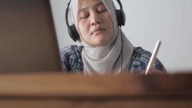 Uykulu Asyalı Müslüman kadın bilgisayarında telekonferans yaparken esniyor, internette öğreniyor ya da ev konseptinden öğreniyor.