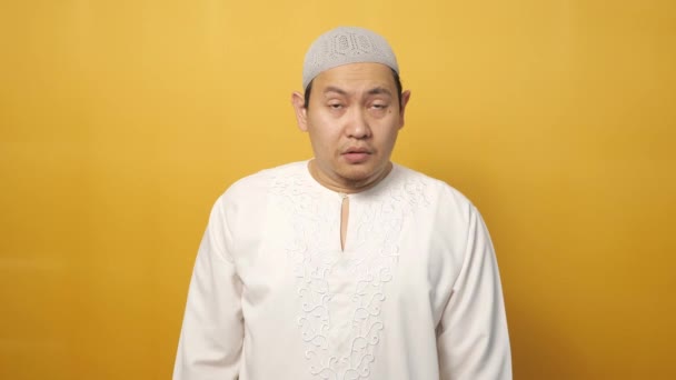 滑稽的亚洲穆斯林男子的画像看上去很担心 害怕某件不好的事 在黄色的背景下咬着他的指甲 — 图库视频影像
