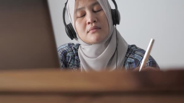 自宅でノートパソコンでビデオ会議を行うときに疲れて眠いアジアのイスラム教徒の女性は オンライン学習や家庭の概念から働く — ストック動画