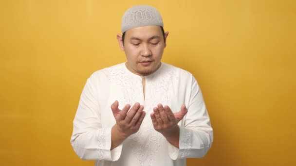 アジアのイスラム教徒の男性の肖像画は 黄色の背景に 立ち上がったジェスチャーの手を祈る 神に祈る — ストック動画