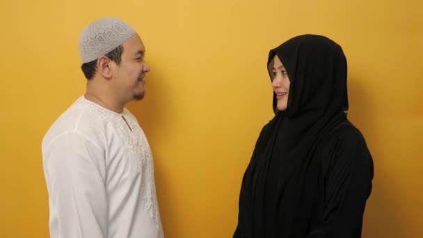 幸せなアジアのイスラム教徒のカップルは 黄色の背景を背景に Eidのムバラクの伝統における挨拶のジェスチャー 謝罪と許しを行う — ストック動画