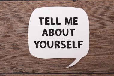 Bana kendinizden bahsedin. Tahta arka plan, hayat ve iş motivasyon konseptine karşı kağıda yazılmış yazı karakterleri.