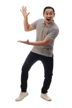 Gri gömlekli, siyah kot ve beyaz ayakkabılı Asyalı bir adam. Şaşırmış, neşeli bir ifade. Fotokopi alanını işaret ediyor. Tüm vücut portresi izole edildi.