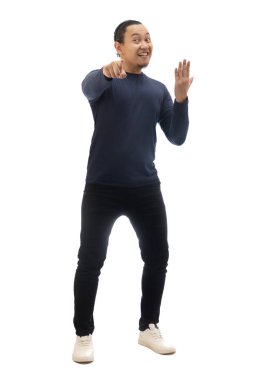 Günlük mavi gömlekli, siyah kot ve beyaz ayakkabılı bir adam kameraya bakıyor, gülümsüyor ve seni jest yapmaya davet ediyor, işe alıyor. Tüm vücut portresi izole edildi.