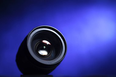Mavi arkaplan üzerindeki ışık altında kamera lensi, fotokopi alanı ile fotoğraf teması konsepti