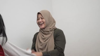 Neşeli Asyalı Müslüman anne ve kızı birlikte gülüyor ve hikayelerini paylaşıyorlar, mutlu aile.