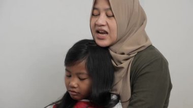 Neşeli Asyalı Müslüman anne ve kızı birlikte gülüyor ve hikayelerini paylaşıyorlar, mutlu aile.