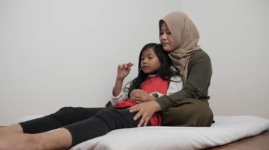 Neşeli Asyalı Müslüman anne ve kızı birlikte gülüyor ve hikayelerini paylaşıyorlar, mutlu aile.