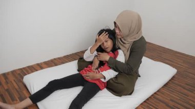 Neşeli Asyalı Müslüman anne ve kızı birlikte gülüyor ve hikayelerini paylaşıyorlar, mutlu aile.