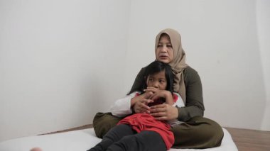 Neşeli Asyalı Müslüman anne ve kızı birlikte gülüyor ve hikayelerini paylaşıyorlar, mutlu aile.