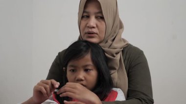 Neşeli Asyalı Müslüman anne ve kızı birlikte gülüyor ve hikayelerini paylaşıyorlar, mutlu aile.