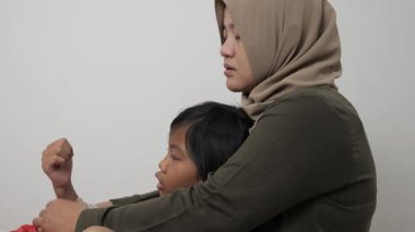 Neşeli Asyalı Müslüman anne ve kızı birlikte gülüyor ve hikayelerini paylaşıyorlar, mutlu aile.