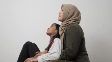 Neşeli Asyalı Müslüman anne ve kızı birlikte gülüyor ve hikayelerini paylaşıyorlar, mutlu aile.