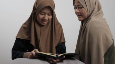 Asyalı Müslüman anne kızına evde Kur 'an okumayı öğretiyor, Arapça yazılar ve Kuran ayetleri öğreniyor.