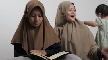 Asyalı Müslüman anne kızına evde Kur 'an okumayı öğretiyor, Arapça yazılar ve Kuran ayetleri öğreniyor.