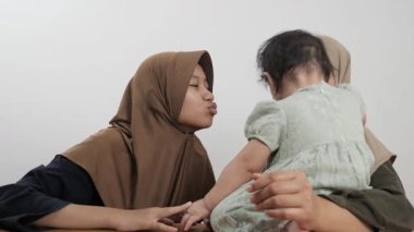 Mutlu Asyalı Müslüman anne yerde oturuyor ve iki kızıyla bağ kuruyor.