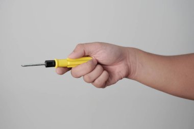 Erkek kişi elinde tornavidayla gri arka planda.