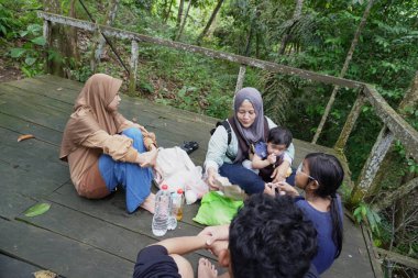 Asyalı Müslüman anne, ormanın ortasında oğlu ve kızıyla piknik yapıyor. Aile bağları kuruyor.