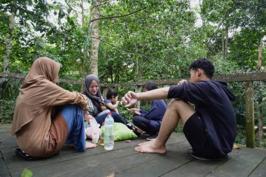Asyalı Müslüman anne, ormanın ortasında oğlu ve kızıyla piknik yapıyor. Aile bağları kuruyor.