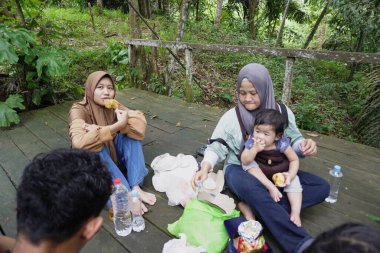 Asyalı Müslüman anne, ormanın ortasında oğlu ve kızıyla piknik yapıyor. Aile bağları kuruyor.