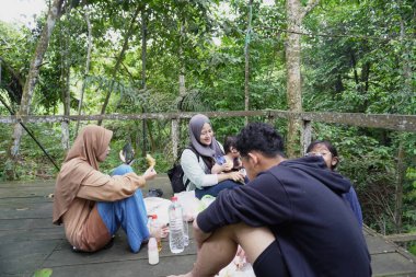 Asyalı Müslüman anne, ormanın ortasında oğlu ve kızıyla piknik yapıyor. Aile bağları kuruyor.