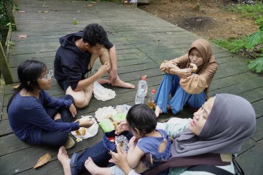 Asyalı Müslüman anne, ormanın ortasında oğlu ve kızıyla piknik yapıyor. Aile bağları kuruyor.