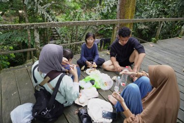 Asyalı Müslüman anne, ormanın ortasında oğlu ve kızıyla piknik yapıyor. Aile bağları kuruyor.