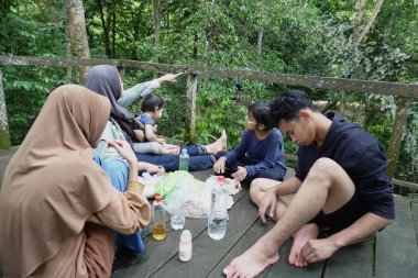 Asyalı Müslüman anne, ormanın ortasında oğlu ve kızıyla piknik yapıyor. Aile bağları kuruyor.