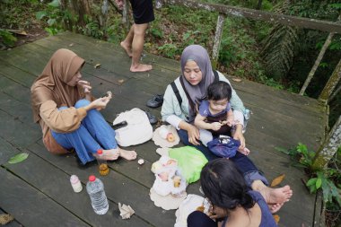 Asyalı Müslüman anne, ormanın ortasında oğlu ve kızıyla piknik yapıyor. Aile bağları kuruyor.