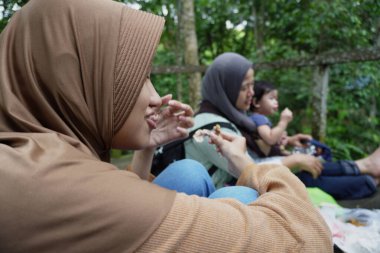Asyalı Müslüman anne, ormanın ortasında oğlu ve kızıyla piknik yapıyor. Aile bağları kuruyor.
