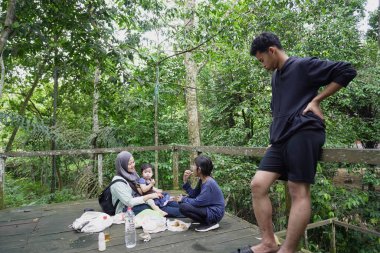 Asyalı Müslüman anne, ormanın ortasında oğlu ve kızıyla piknik yapıyor. Aile bağları kuruyor.