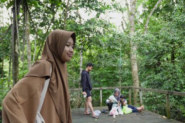 Asyalı Müslüman anne, ormanın ortasında oğlu ve kızıyla piknik yapıyor. Aile bağları kuruyor.