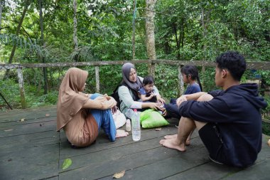 Asyalı Müslüman anne, ormanın ortasında oğlu ve kızıyla piknik yapıyor. Aile bağları kuruyor.