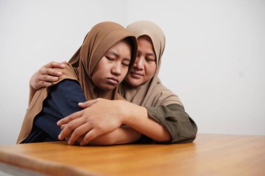 Asyalı Müslüman anne, üzgün kızını teselli ediyor, çocuğa duygusal destek veriyor, zor bir günün ardından stresle başa çıkıyor veya zorbalıkla başa çıkıyor.