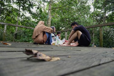 Asyalı Müslüman anne, ormanın ortasında oğlu ve kızıyla piknik yapıyor. Aile bağları kuruyor.