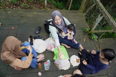 Asyalı Müslüman anne, ormanın ortasında oğlu ve kızıyla piknik yapıyor. Aile bağları kuruyor.