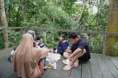 Asyalı Müslüman anne, ormanın ortasında oğlu ve kızıyla piknik yapıyor. Aile bağları kuruyor.