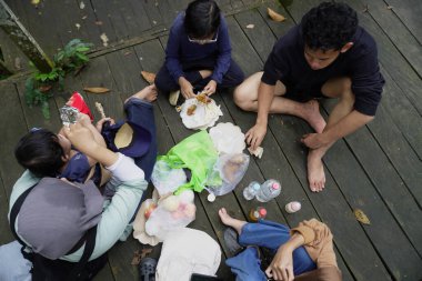 Asyalı Müslüman anne, ormanın ortasında oğlu ve kızıyla piknik yapıyor. Aile bağları kuruyor.
