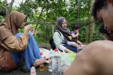 Asyalı Müslüman anne, ormanın ortasında oğlu ve kızıyla piknik yapıyor. Aile bağları kuruyor.
