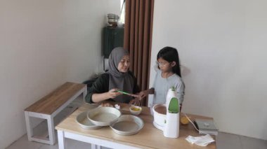 Asyalı Müslüman anne kızıyla pasta yapıyor, aile yemeği kavramı, elektrikli mikserde hamuru karıştırıyor.
