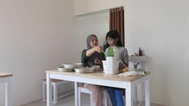 Asyalı Müslüman anne kızıyla pasta yapıyor, aile yemeği kavramı, hamuru pişirme tavasına döküyor.