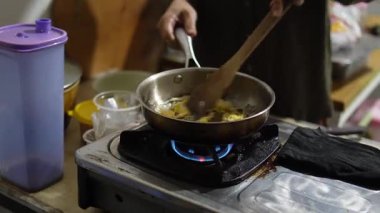 İsimsiz kadın ellerinin kızartma tavasında çırpılmış yumurta pişirmesi, ev mutfağında kahvaltıda spatulayla yumurta çırpması.