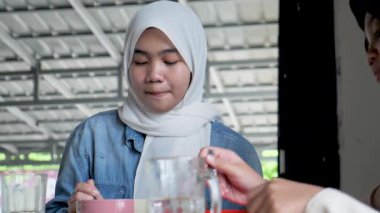 Bir kafede arkadaşıyla yemek yerken gülümseyen ve gülen güzel Asyalı Müslüman bir genç kızın portresini yakından çek.