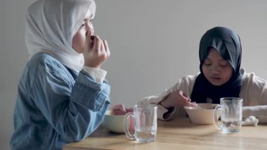 İki güzel Asyalı Müslüman genç kız bir kafede öğle yemeği yiyor. Barışçıl bir ortamda konuşup gülüyorlar.