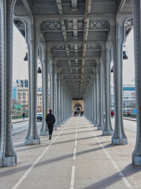 Bir-Hakeim Köprüsü Altında Yürüyüş - Pont de Bir-Hakeim 'in metalik yapısının altındaki yaya geçidinin simetrik perspektifi tek bir kişinin yürüyüp gitmesiyle ve doğal ışığın sonunda.